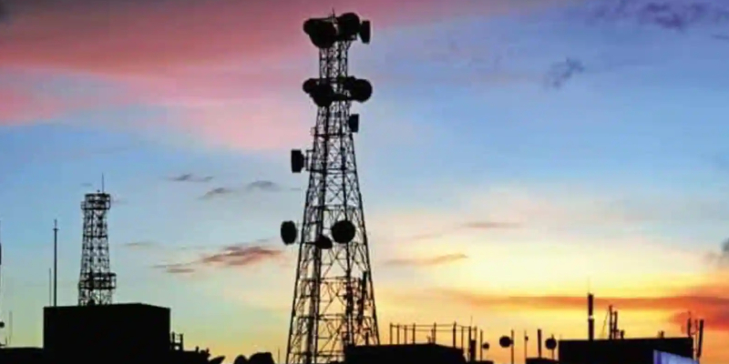 Two telecom towers are seen among tall buildings, red sky is there as a background.
